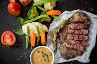 Grilled steak served with fresh vegetables and pepper sauce, presenting a colorful and appetizing meal.