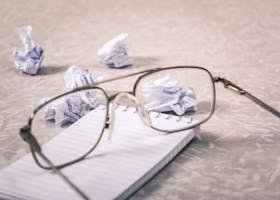 Eyeglasses and crumpled paper on notepad, symbolizing creative brainstorming process.